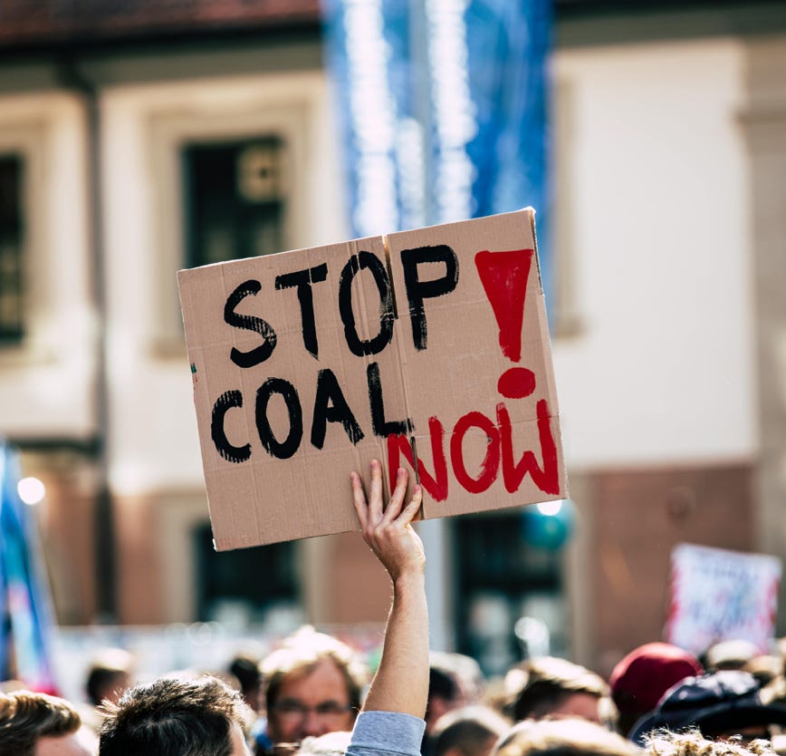 Stop Coal Now sign held up above crowd at protest